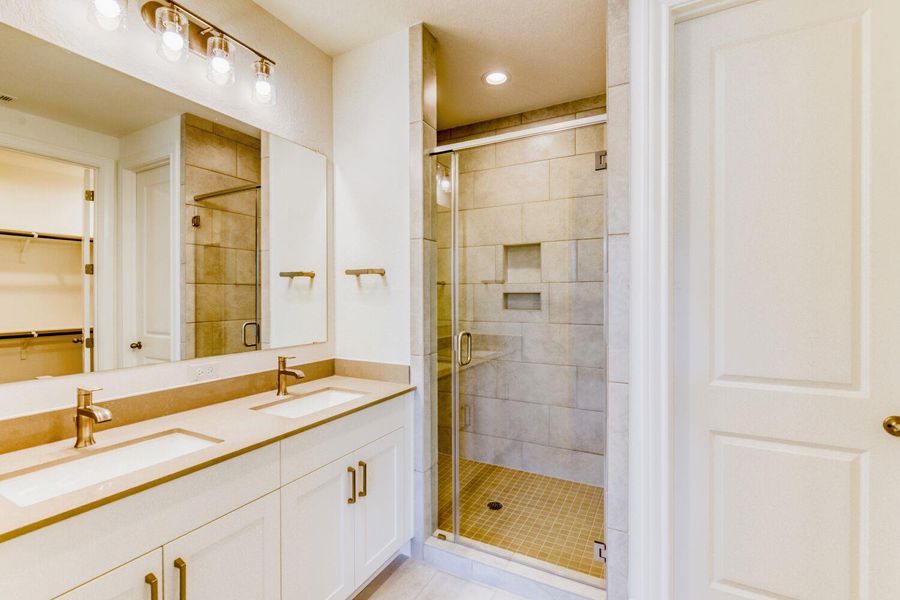 Bathroom with double vanity, a spacious closet, a shower stall, and recessed lighting