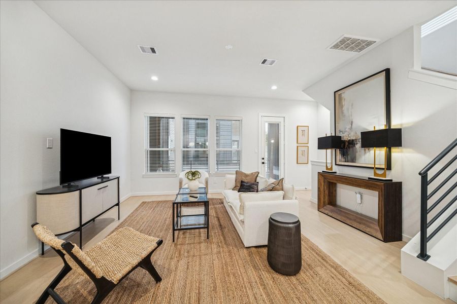 Comfortable living area offers a welcoming layout with direct access to the balcony for easy indoor-outdoor living. Neutral tones and layered textures bring warmth to the open concept space, creating an inviting area for conversation or quiet evenings at home.