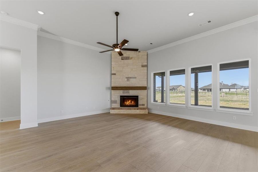 Unfurnished living room featuring a ceiling fan, a fireplace, light wood-style flooring, crown molding, and recessed lighting Unfurnished living room featuring a ceiling fan, a fireplace, light wood-style flooring, crown molding, and recessed lighting