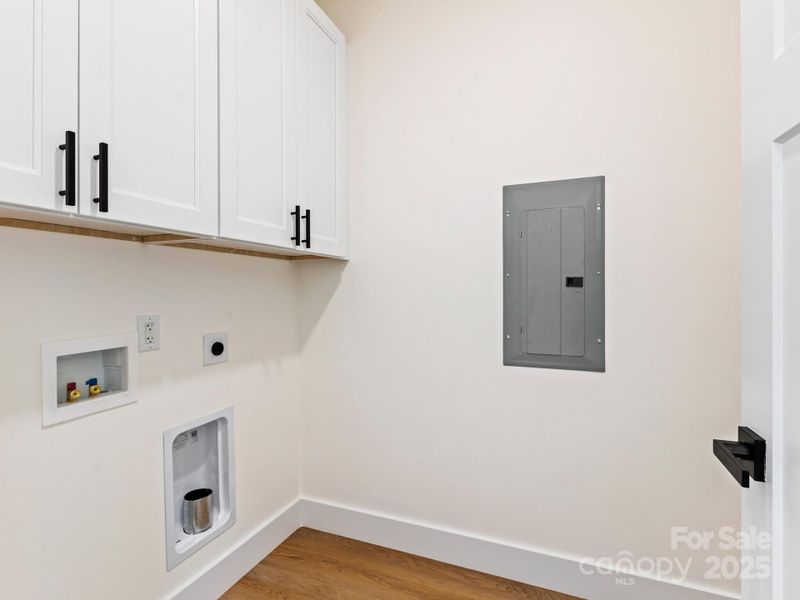 Laundry room comes with cabinets for storage and space for a side by side washer and dryer