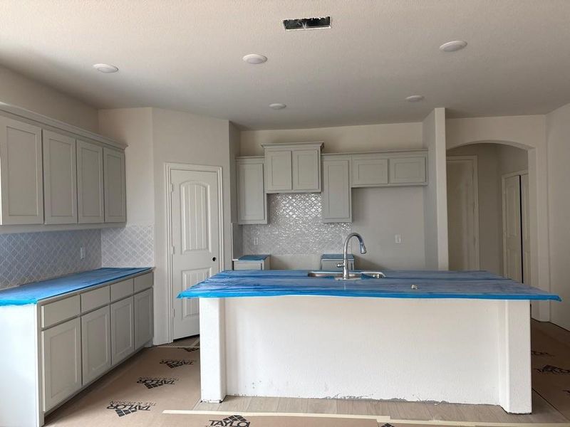 Spacious kitchen featuring white shaker-style cabinetry, a large central island with an undermount sink, and recessed lighting