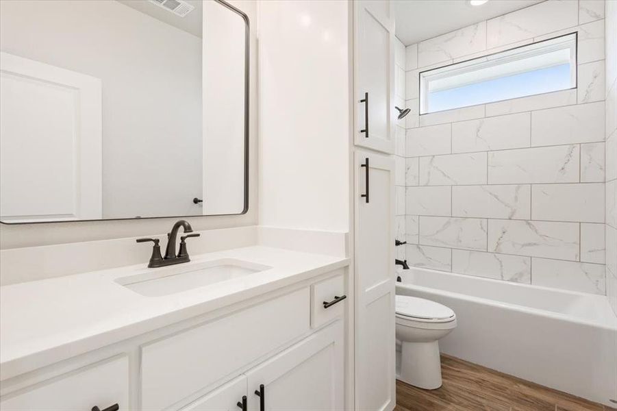 Full bathroom with bathtub / shower combination, vanity, visible vents, toilet, and wood finished floors