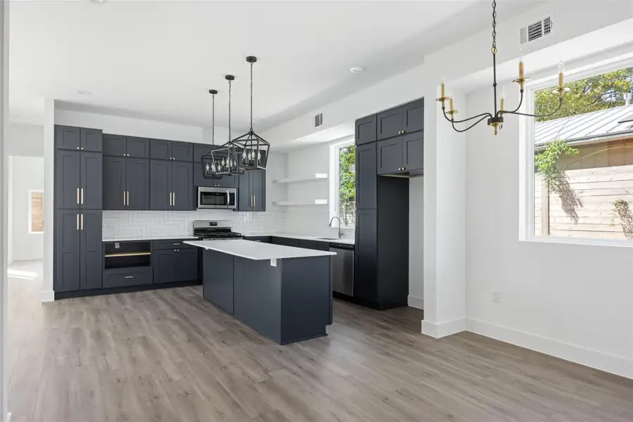 Kitchen featuring a chandelier, open shelves, a kitchen island, decorative light fixtures, and a kitchen breakfast bar Kitchen featuring a chandelier, open shelves, a kitchen island, decorative light fixtures, and a kitchen breakfast bar