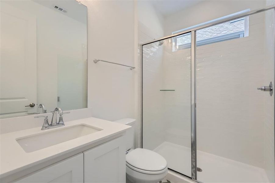 Bathroom featuring vanity, toilet, and a shower with door