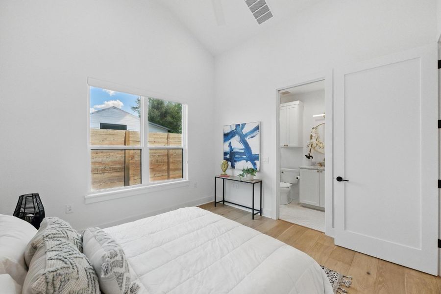 Bedroom with light wood-type flooring, lofted ceiling, and ensuite bathroom Bedroom with light wood-type flooring, lofted ceiling, and ensuite bathroom