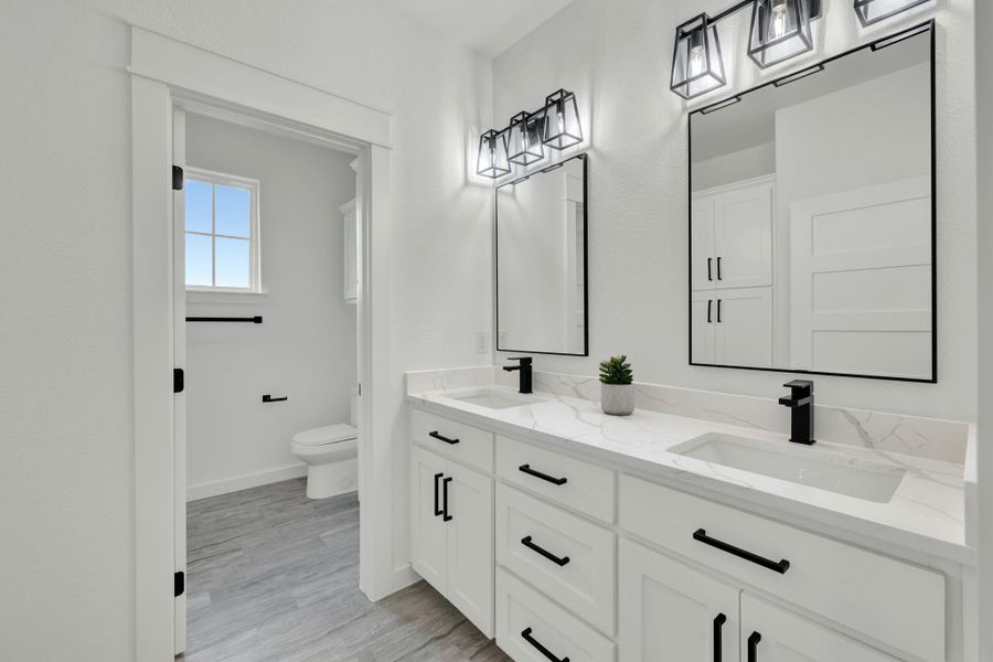 Double vanity featuring white cabinetry, integrated sinks, and quartz countertops with black matte fixtures