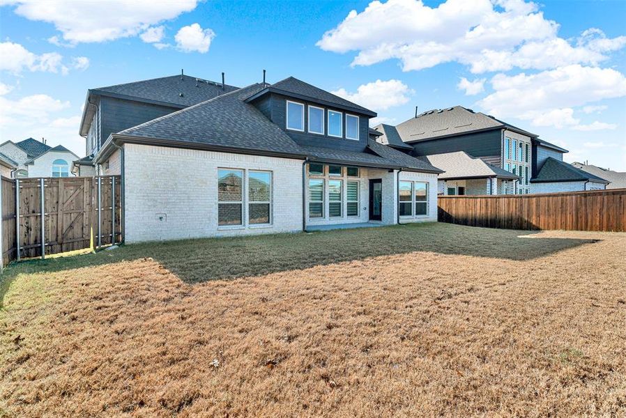Back of house with a patio, a shingled roof, brick siding, a fenced backyard, and a gate Back of house with a patio, a shingled roof, brick siding, a fenced backyard, and a gate