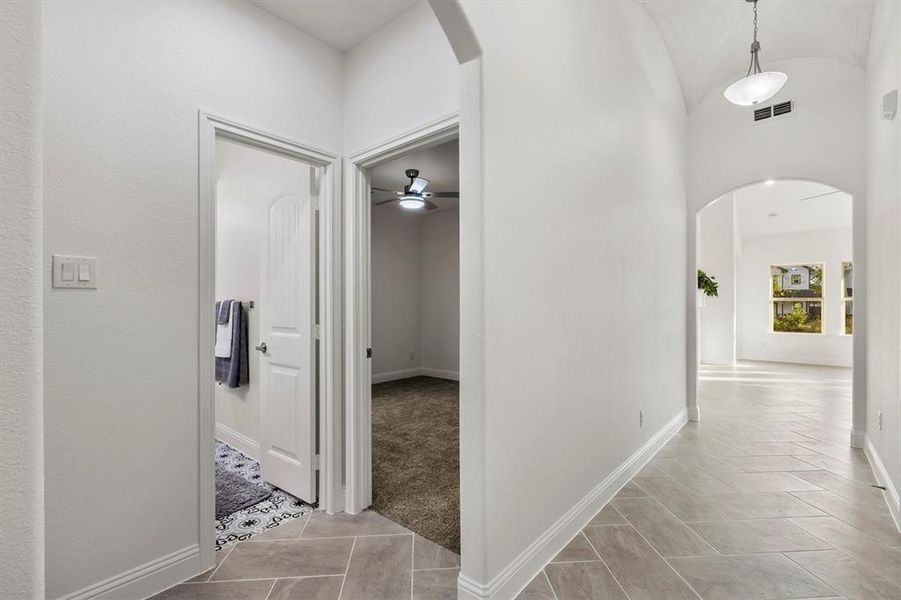 Hallway featuring vaulted ceiling and light colored carpet