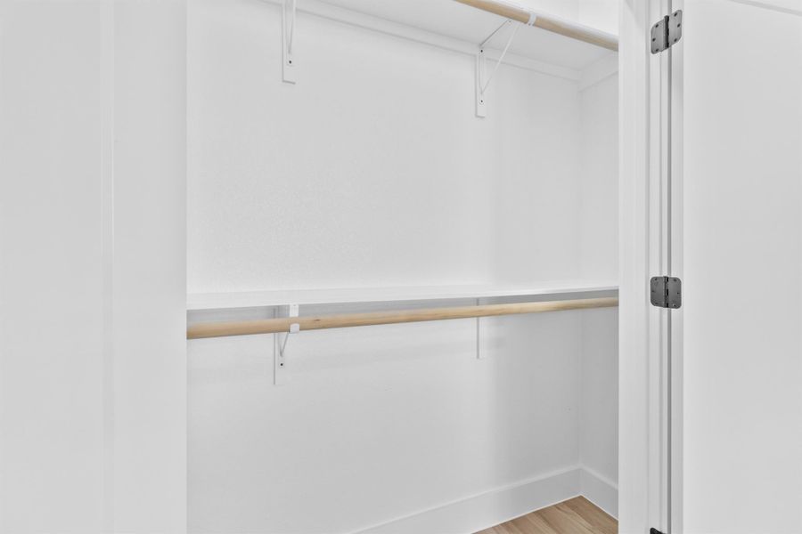 Walk in closet with light wood finished floors