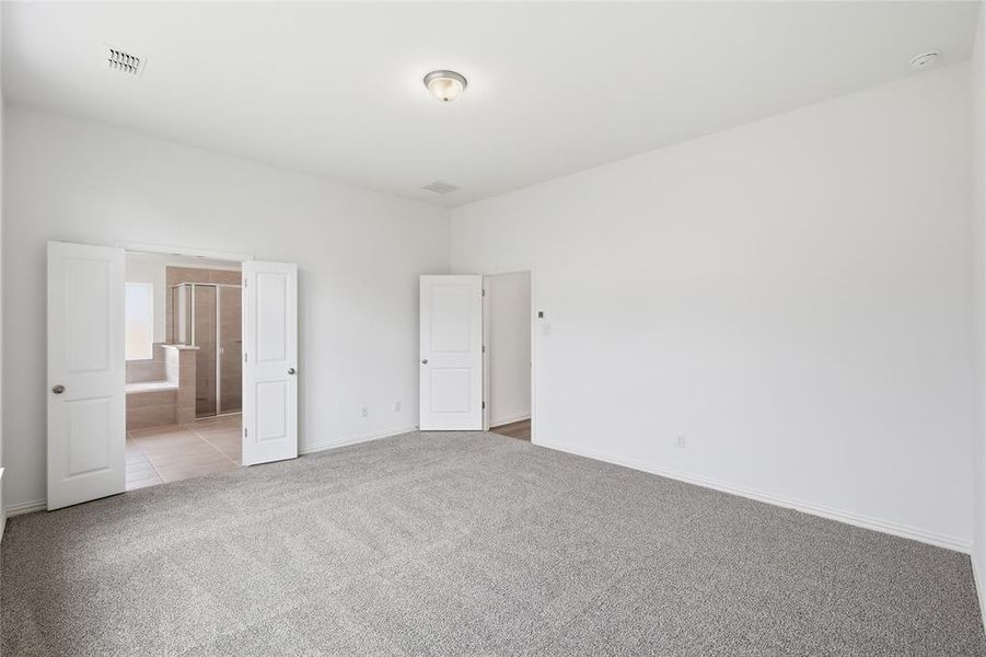 Spacious carpeted room featuring a ceiling-mounted light fixture, white walls, and white trim
