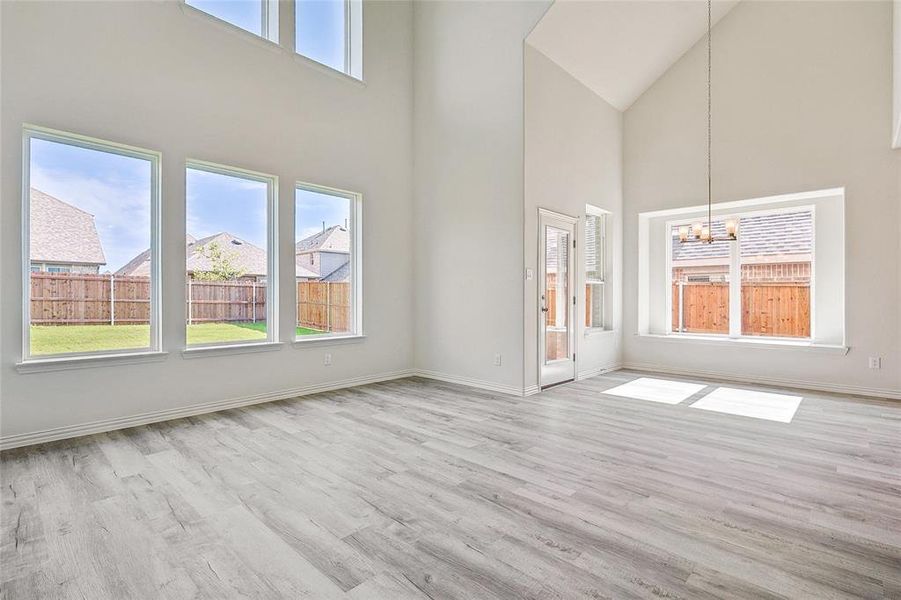 Unfurnished living room featuring a high ceiling, light hardwood / wood-style flooring, and a notable chandelier