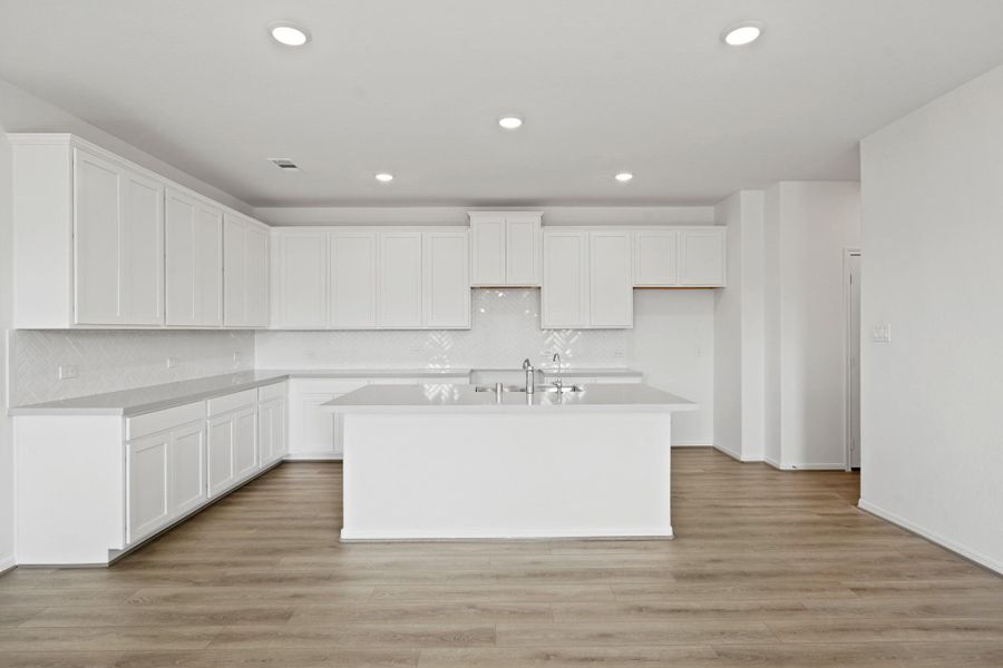 This light and bright kitchen features a large quartz island, white cabinets, a large sink overlooking your family room, recessed lighting, and beautiful backsplash. This light and bright kitchen features a large quartz island, white cabinets, a large sink overlooking your family room, recessed lighting, and beautiful backsplash.