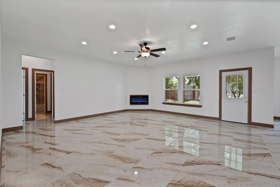 Unfurnished living room with light marble finish floors, recessed lighting, a glass covered fireplace, and a ceiling fan