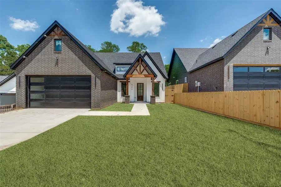 Contemporary home exterior featuring a dark brick and white facade, an attached garage with a modern glass-paneled door, and a covered entry with wood beam accents Contemporary home exterior featuring a dark brick and white facade, an attached garage with a modern glass-paneled door, and a covered entry with wood beam accents