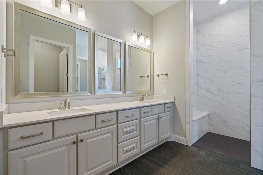 Enjoy a double vanity, quartz countertops, and upgraded mirrors in this owner's en suite.