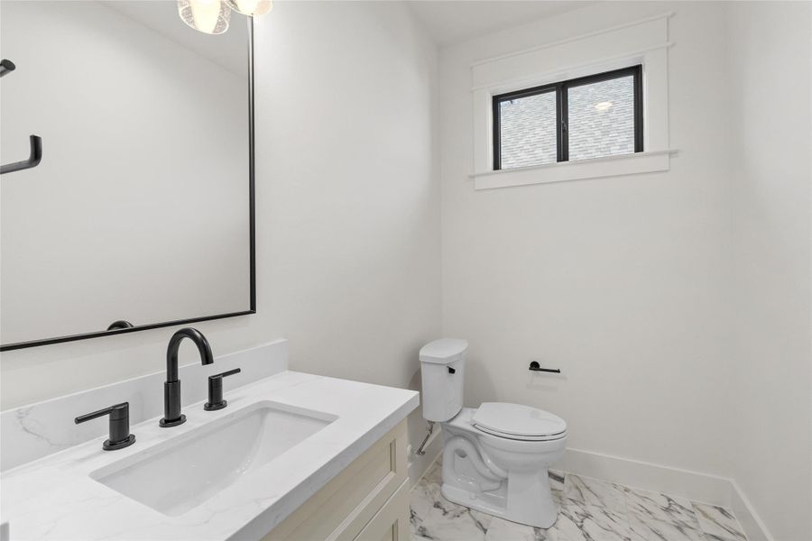 Your guest bath keeps things crisp and modern with a quartz countertop, sleek undermount sink, and matte black fixtures that add just the right amount of contrast. Marble-style flooring and a large mirror give the space a polished, hotel-inspired feel that’s both functional and stylish.