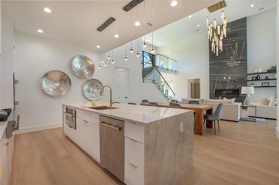 Kitchen with pendant lighting, a large island with sink, white cabinets, light hardwood / wood-style flooring, and stainless steel appliances