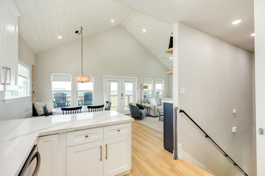The open-concept layout combines the kitchen, dining, and living areas beneath vaulted ceilings, creating an inviting space for gathering with family and friends.