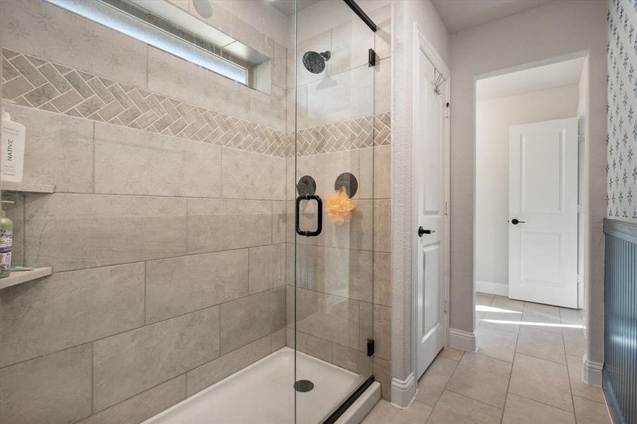 Bathroom with light tile patterned flooring and a shower stall