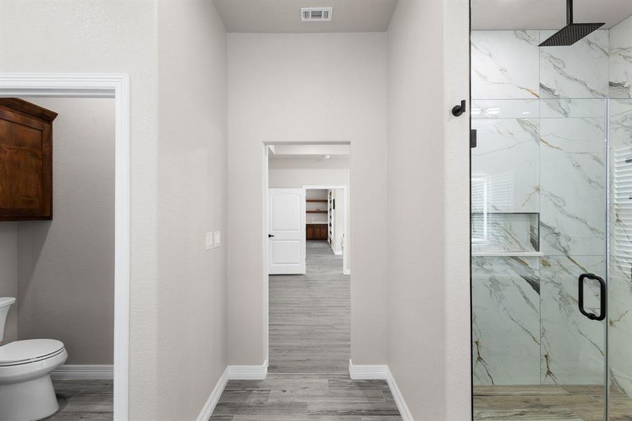 Bathroom with a marble finish shower and light wood-style flooring