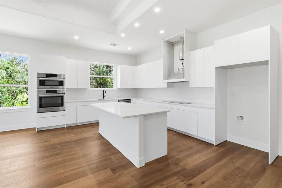 A sleek, contemporary kitchen with pristine white cabinetry, quartz countertops, and lustrous wood flooring. A sleek, contemporary kitchen with pristine white cabinetry, quartz countertops, and lustrous wood flooring.