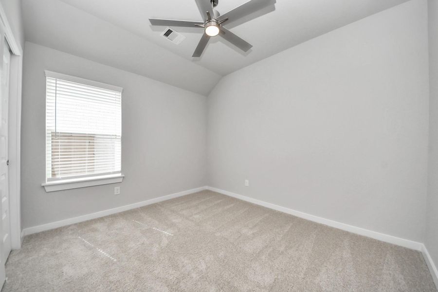 Secondary bedroom features plush carpeting, large windows that let in plenty of natural light, bright paint, and spacious closets. Sample photo of completed home with similar floor plan. Actual colors and selections may vary.