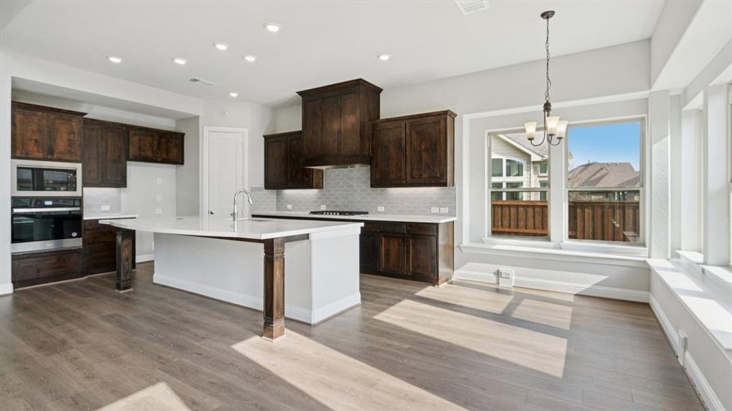 Kitchen with stainless steel appliances, dark brown cabinets, decorative backsplash, and recessed lighting Kitchen with stainless steel appliances, dark brown cabinets, decorative backsplash, and recessed lighting