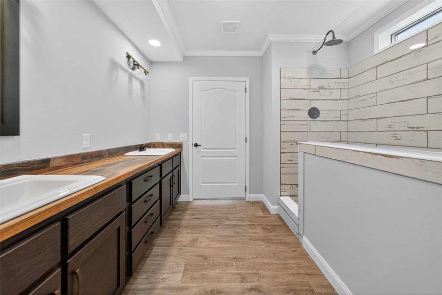 Bathroom featuring ornamental molding, walk in shower, double vanity, light wood finished floors, and recessed lighting Bathroom featuring ornamental molding, walk in shower, double vanity, light wood finished floors, and recessed lighting