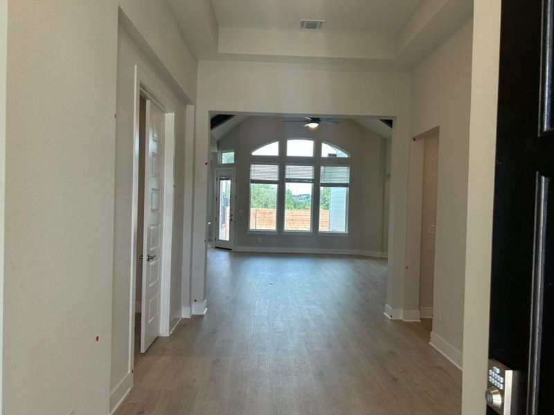 Corridor with light wood finished floors and a raised ceiling