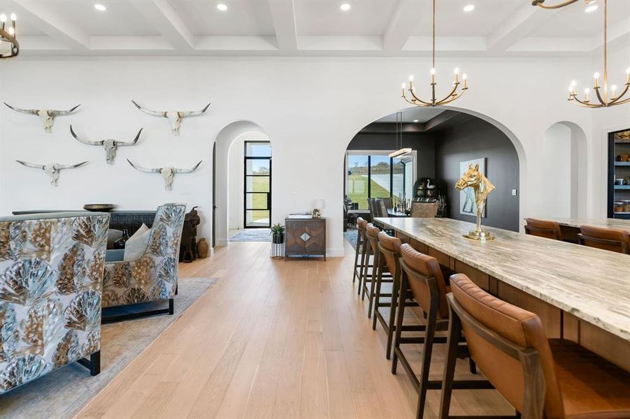 Dining area with arched walkways, light wood finished floors, a chandelier, beamed ceiling, and recessed lighting Dining area with arched walkways, light wood finished floors, a chandelier, beamed ceiling, and recessed lighting