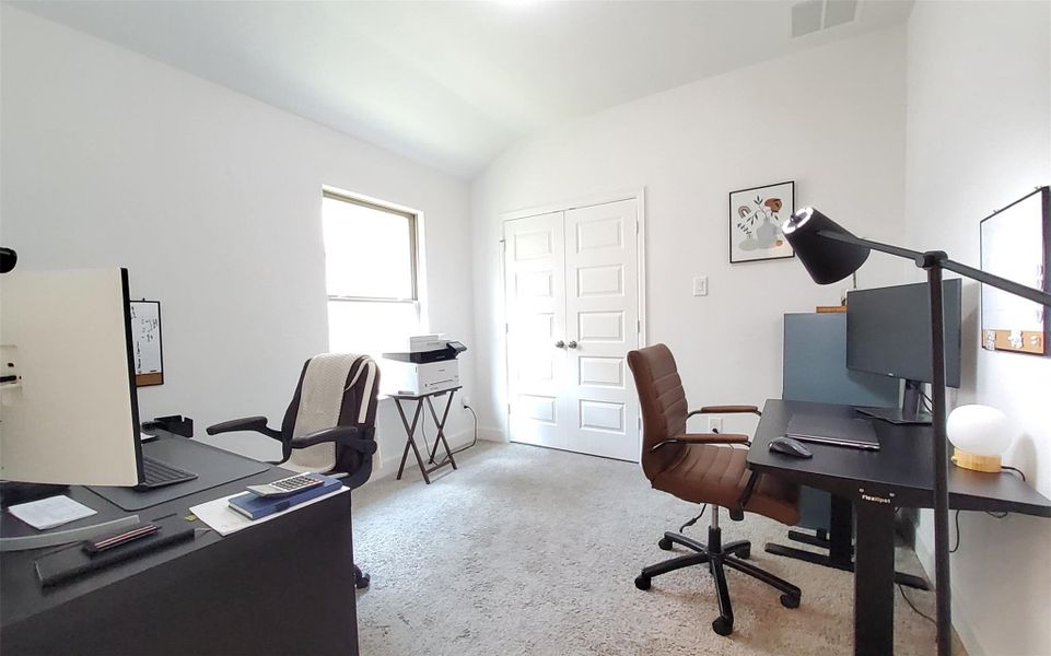 Bright home office featuring dual workstations, modern furniture, and ample natural light from a large window.