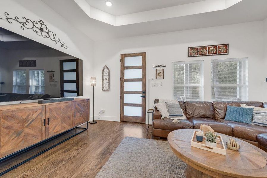 Living area featuring a tray ceiling and dark wood-style flooring