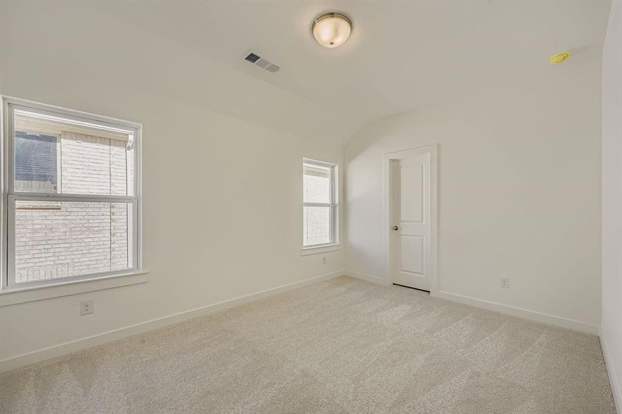 Empty room with light carpet and vaulted ceiling