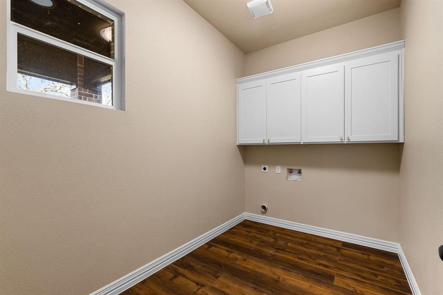 Laundry room with dark wood-type flooring, cabinets, washer hookup, and electric dryer hookup