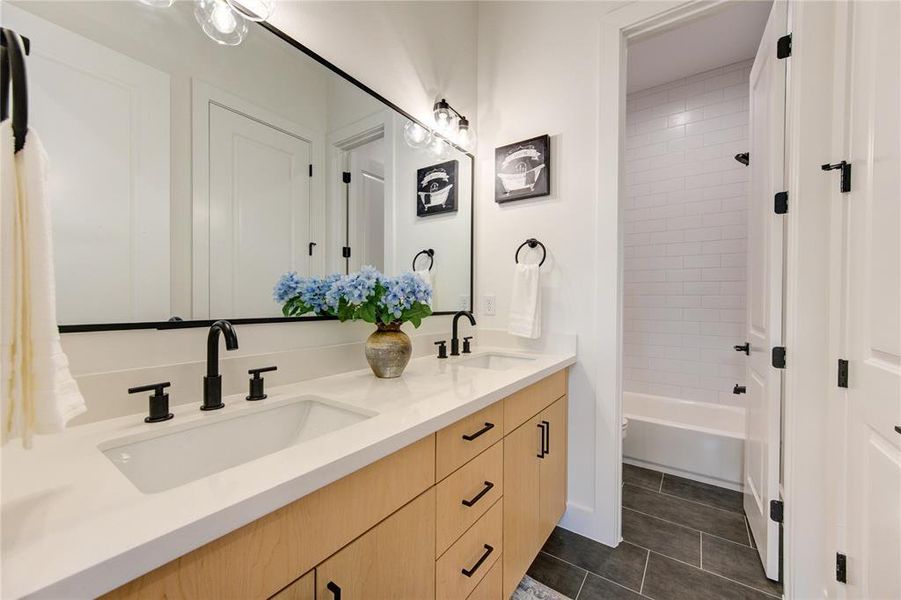 Guest Bathroom. Bathtub features beautiful subway tiles and contrasting black trim. Double vanity and separate room for toilet/shower makes this ideal for roommates or children.