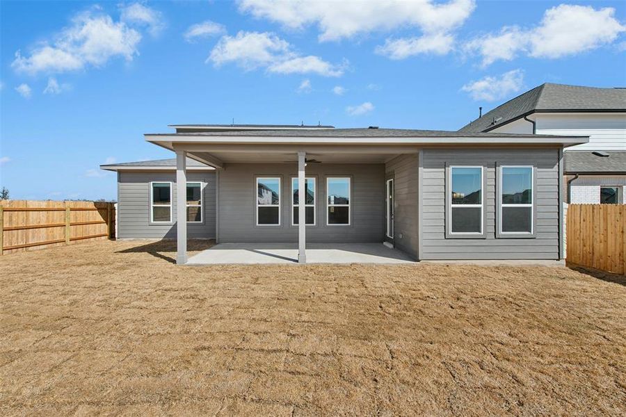 Expansive backyard featuring a covered patio, multiple windows, and a newly installed wood fence