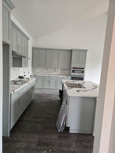 Kitchen featuring sink, gray cabinets, appliances with stainless steel finishes, high vaulted ceiling, and tasteful backsplash