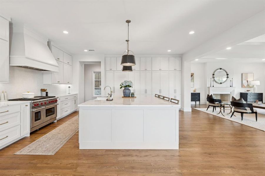 Kitchen featuring custom range hood, recessed lighting, white cabinets, range with two ovens, and light wood-style flooring Kitchen featuring custom range hood, recessed lighting, white cabinets, range with two ovens, and light wood-style flooring