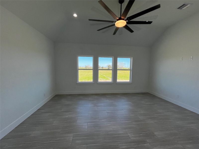 Spacious room with light-colored tile flooring, large windows offering plenty of natural light and scenic views, and a modern ceiling fan.