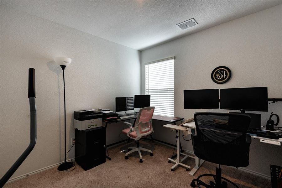 Carpeted office space with a textured ceiling