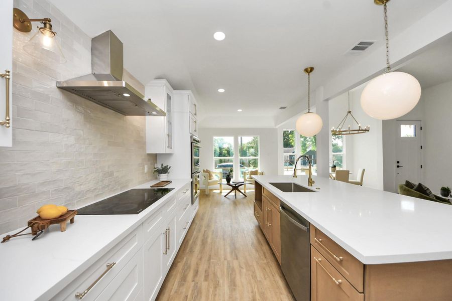 A beautifully curated kitchen where modern white cabinetry with glass accents meets warm brass hardware and soft, ambient lighting. The sleek induction cooktop and stainless steel range hood offer a streamlined look, while a beige subway tile backsplash brings just the right touch of warmth and texture. A beautifully curated kitchen where modern white cabinetry with glass accents meets warm brass hardware and soft, ambient lighting. The sleek induction cooktop and stainless steel range hood offer a streamlined look, while a beige subway tile backsplash brings just the right touch of warmth and texture.