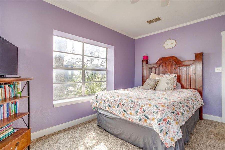 Bedroom with ornamental molding, light colored carpet, and ceiling fan