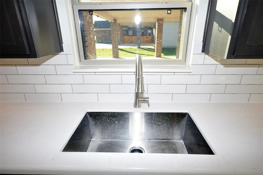 Large undercounted single bowl sink with a window above.