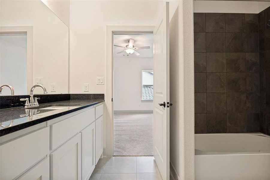 Bathroom vanity featuring a dark countertop, white cabinetry, and brushed nickel fixtures Bathroom vanity featuring a dark countertop, white cabinetry, and brushed nickel fixtures