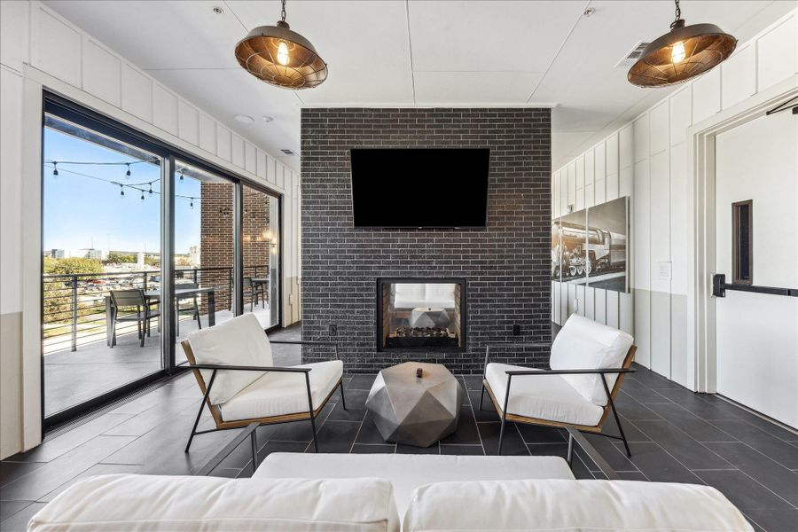 A chic living space featuring a modern fireplace, balcony access, and industrial-style lighting. A chic living space featuring a modern fireplace, balcony access, and industrial-style lighting.