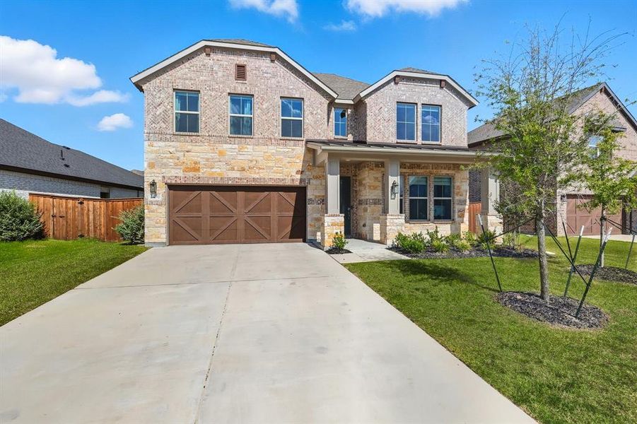 View of front of property with brick siding, driveway, a garage, covered porch, and stone siding View of front of property with brick siding, driveway, a garage, covered porch, and stone siding