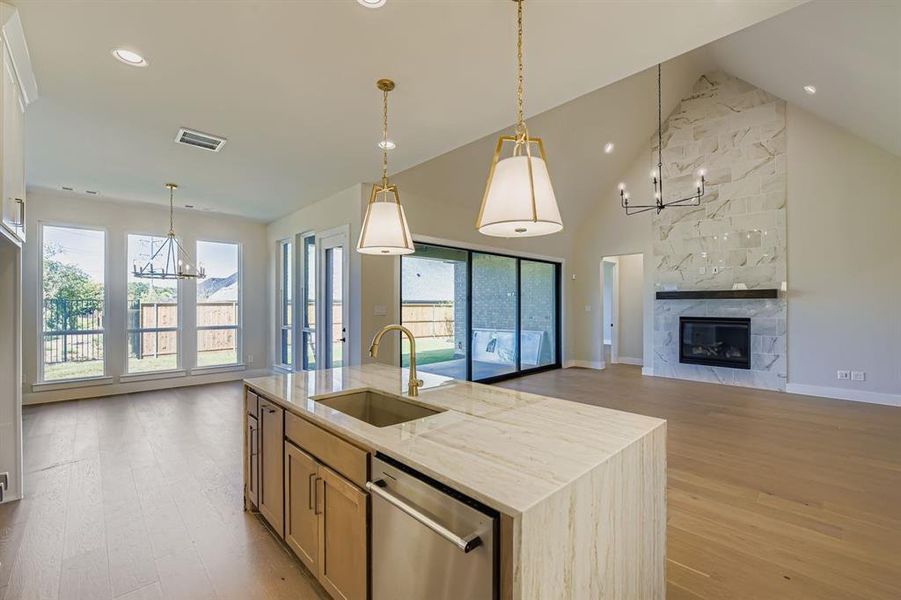 Kitchen featuring a chandelier, open floor plan, light stone countertops, high vaulted ceiling, and light wood-style flooring