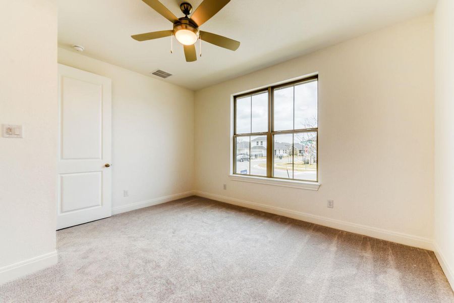 Empty room with light carpet and a ceiling fan