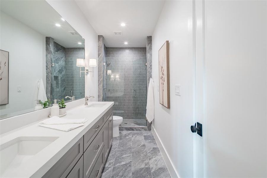 Bathroom featuring tiled shower, vanity, and toilet