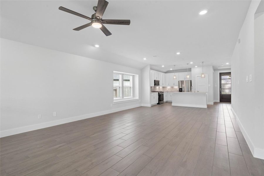 This expansive view from the back of the house showcases a seamless, open-concept layout that creates a warm and inviting path.